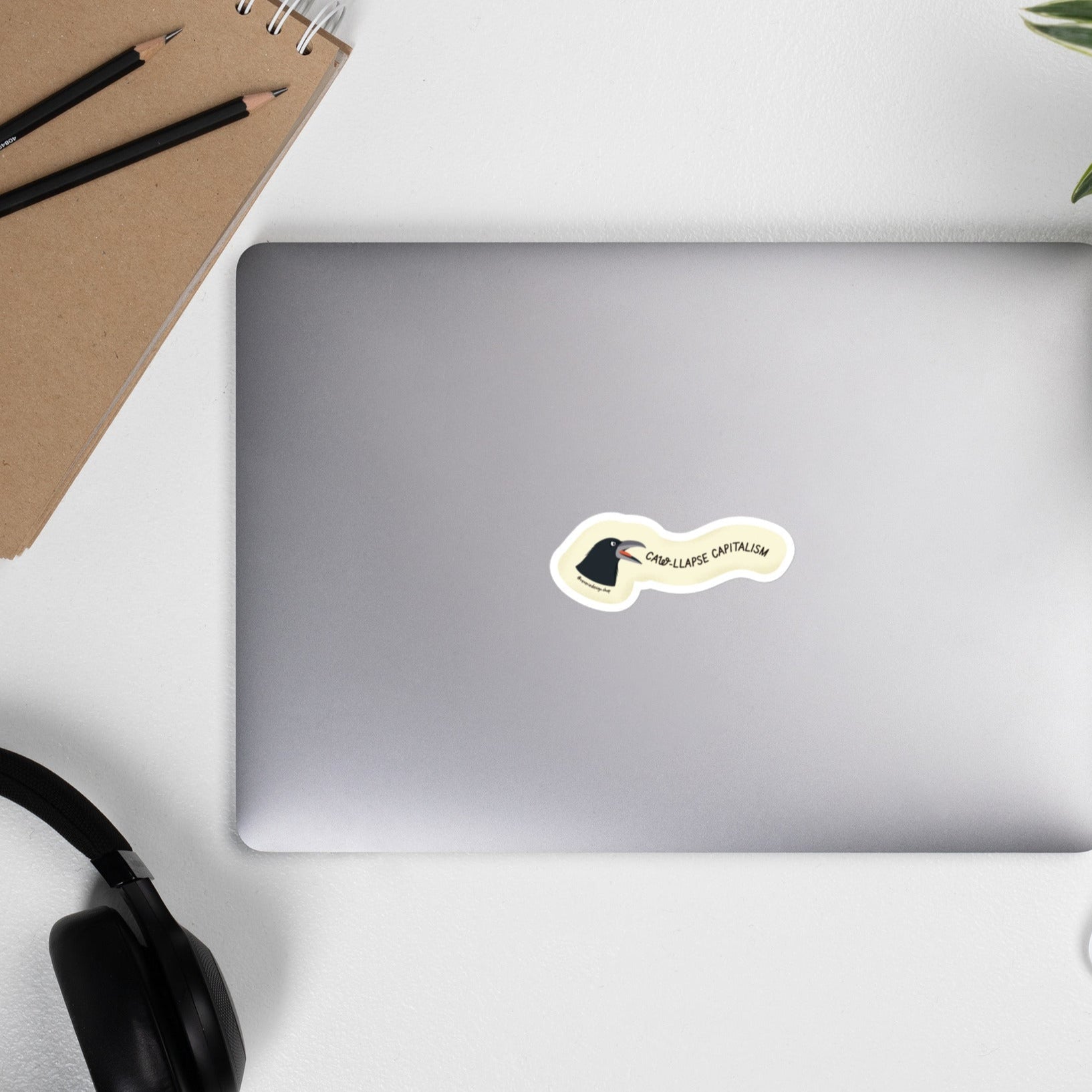 Laptop with Angry crow sticker with text ‘Caw-llapse Capitalism’ in bold